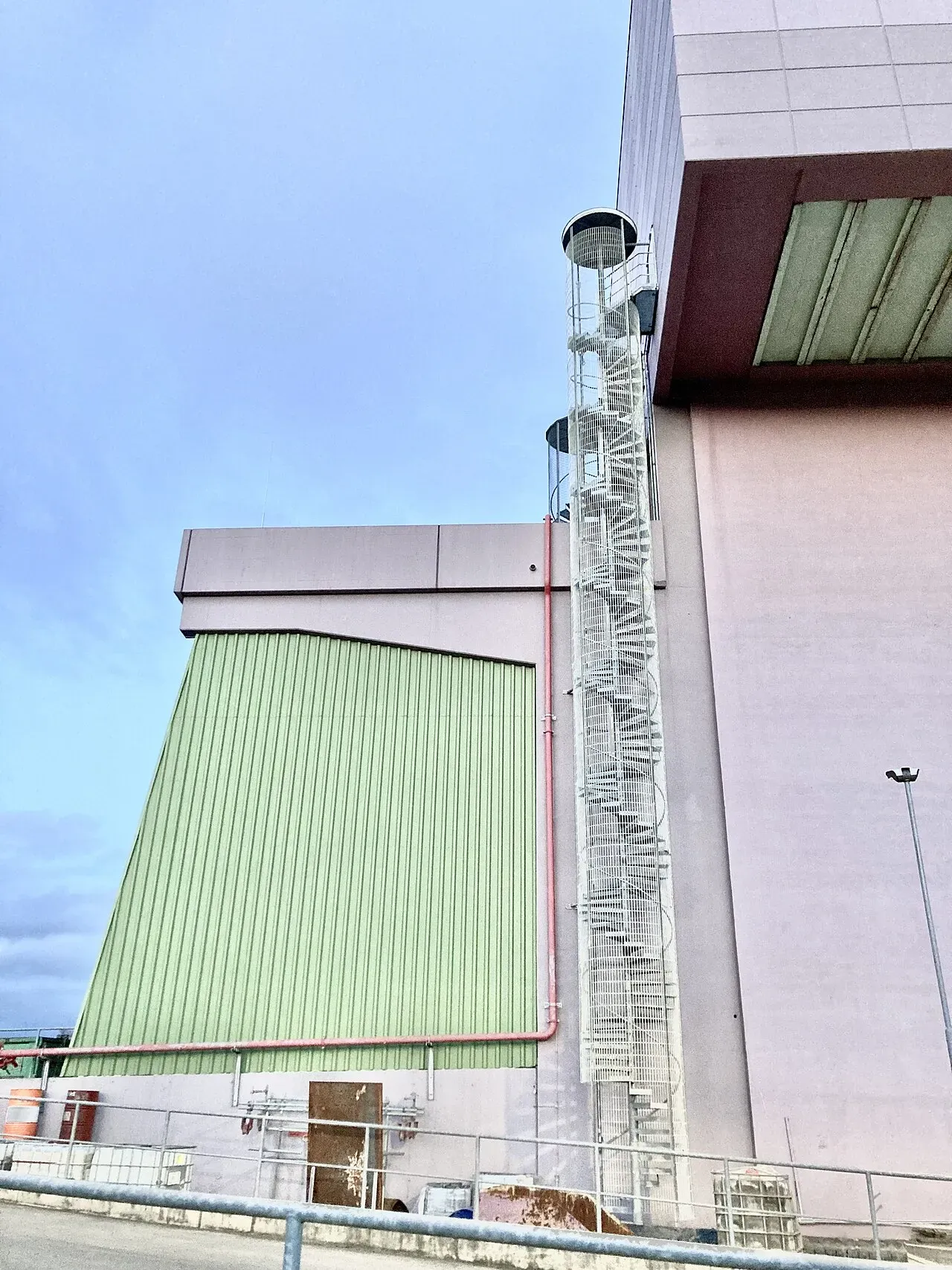 Fassade der Müllverwertungsanlage Bonn in Endenich mit grünem Hallenteil und außenliegender Wendeltreppe